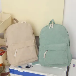 Detailed view of beige and green corduroy student backpacks with minimalist school style