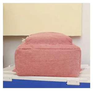 Close-up bottom view of a pink corduroy backpack showcasing its soft ribbed fabric texture