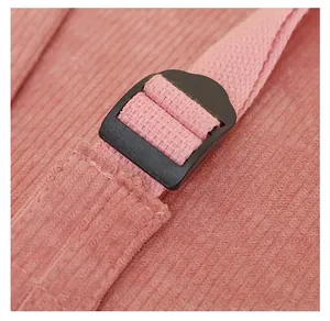 Macro detail of adjustable black plastic buckle and pink corduroy strap on school backpack