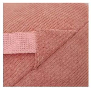 Macro view showing the reinforced stitching and corduroy fabric of a pink backpack