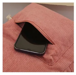 Close-up detail of a pink corduroy backpack front zipper pocket with a smartphone