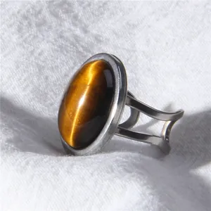 Macro view of a minimalist silver oval tiger's eye ring placed on textured white fabric