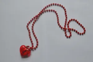 Detail view of a red beaded necklace featuring a glowing LED heart-shaped pendant.