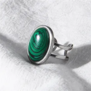 Close-up detail of a minimalist silver ring with an oval green malachite stone