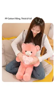 Mannequin asiatique serrant un ours en peluche rose avec un cœur I Love You brodé.