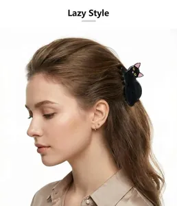 Detailed side view of a cute black cat hair claw clip worn on wavy light brown hair.