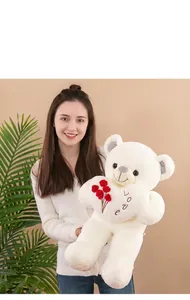 Gros plan d'un gros ours en peluche blanc avec un cœur Love tenu par une femme