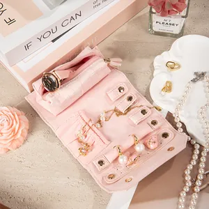 Portable pink crocodile embossed jewelry roll organizer for travel storage.