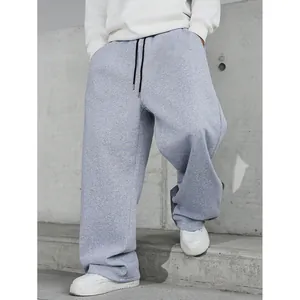 Détail d'un pantalon de jogging gris ample avec cordon de serrage et baskets.