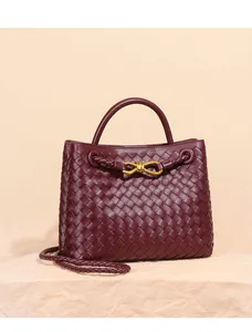 Vista dettagliata della borsa tote in pelle intrecciata bordeaux con fibbia a fiocco
