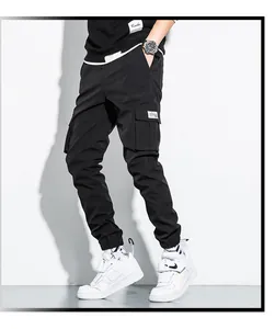 Professional model wearing black multi-pocket cargo joggers in a minimalist studio setting
