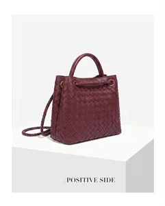 Profilo laterale di una borsa a mano in pelle intrecciata bordeaux con manico superiore
