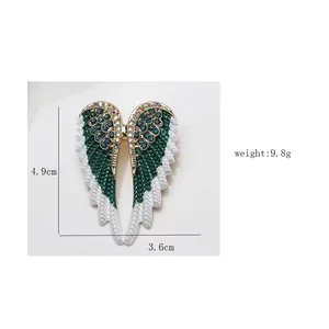 Detailed view of green enamel angel wing brooch with dimension labels 4.9cm height and weight