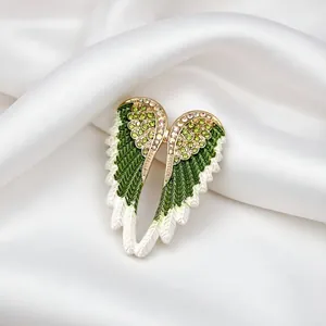 Detailed close-up of green enamel and crystal rhinestones on an angel wing brooch