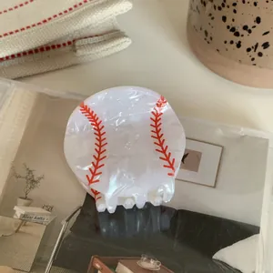 Detail shot of a white acrylic baseball hair claw clip with red stitching patterns
