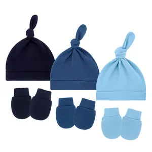 Close-up of three baby knot hats and matching anti-scratch mittens in blue gradients