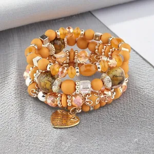 Close-up of bohemian beaded bracelet stack with multilingual heart charm
