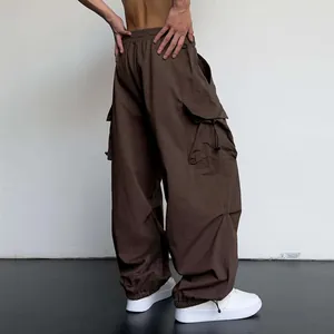 Detail view of brown nylon parachute cargo pants with oversized pockets and drawstring hem