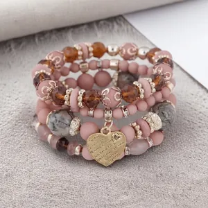 Detailed view of Bohemian stacked beaded bracelets with an engraved heart charm.