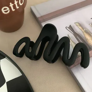 Close-up of matte black wavy hair claw clip showing the unique curved design