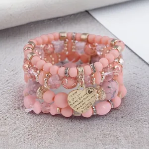 Close-up of pink Bohemian beaded bracelet set with engraved gold heart pendant