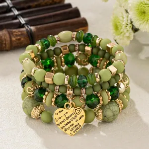 Close-up of Bohemian green beaded stacking bracelet with engraved heart pendant
