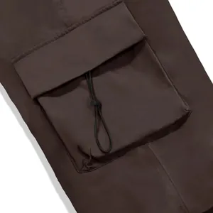 Detailed view of the large cargo pocket with drawstring on brown quick-dry nylon pants.