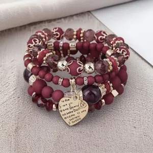 Detailed view of Bohemian burgundy beaded bracelets with gold accents and heart charm