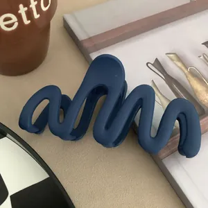 Detail view of a matte navy blue wavy hair claw clip showing its smooth texture
