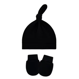 Set of black ribbed baby knot hat and matching anti-scratch mittens on white background
