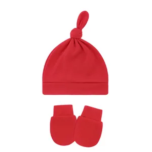 High-quality detailed view of red cotton baby knot hat and matching mittens set