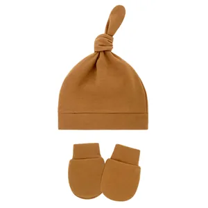 Soft cotton infant knot hat and anti-scratch mittens set in a solid caramel brown color.