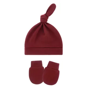 Detail view of soft burgundy baby topknot beanie hat and anti-scratch mittens set
