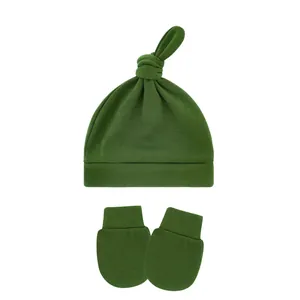 Close-up view of a green knotted baby beanie and matching anti-scratch mittens set