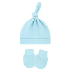 Macro detail view of a soft light blue baby top-knot hat with matching scratch mittens set