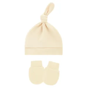 Close-up view of soft cream baby knotted hat and matching anti-scratch mittens set