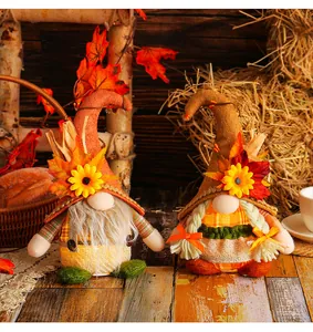 Macro view of a pair of fall harvest gnomes with sunflowers and maple leaf decorations.