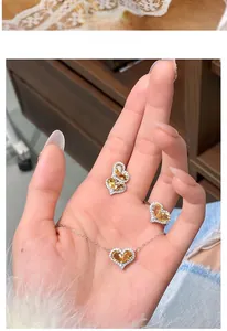 Detailed view of heart-shaped yellow crystal jewelry set held in hand.