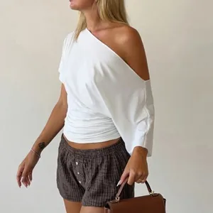 Close-up of white one-shoulder asymmetrical T-shirt showing slim fit and pleated waist