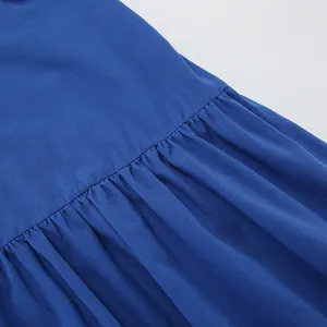 Macro detail of breathable blue cotton linen fabric showing pleated tiered seam on dress