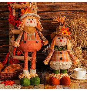 Pair of Thanksgiving scarecrow plush dolls with maple leaf straw hats in a rustic farmhouse setting
