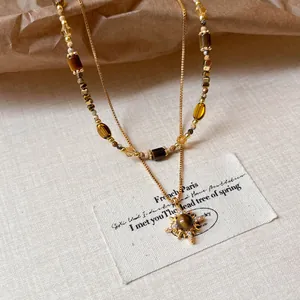 Vintage layered gold necklace with tiger eye beads and sun pendant detail
