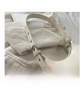 Close-up detail of a white minimalist textured underarm crescent bag with silver hardware