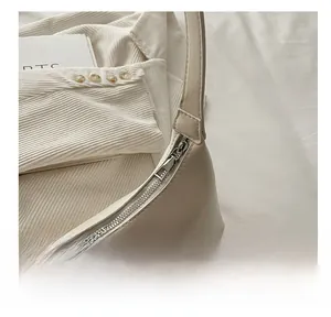 Macro view of a high-quality smooth metal zipper on an off-white underarm bag