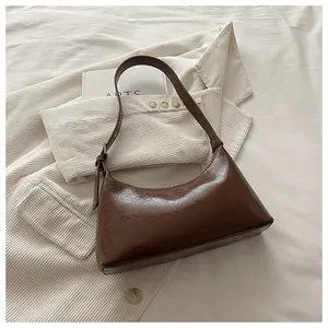 Stylish vintage brown faux leather underarm bag placed on white corduroy outfit
