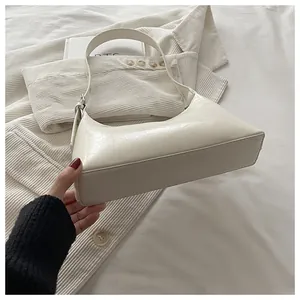 Detailed close-up of a cream minimalist underarm bag with textured leather finish
