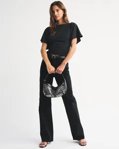 Stylish model wearing black batwing sleeve ruched waist crop top with studded handbag.