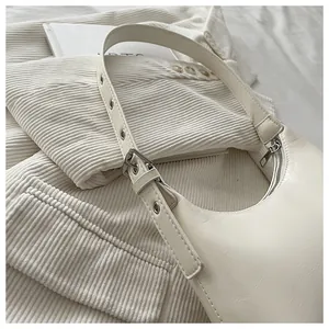 Close-up detail of a creamy white hobo underarm bag with silver buckle strap.