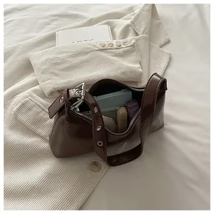 Macro view of a dark brown glossy underarm bag with interior items shown