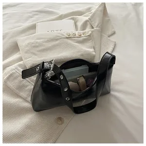 Detail view showing capacity of a stylish glossy black underarm bag with silver grommets.